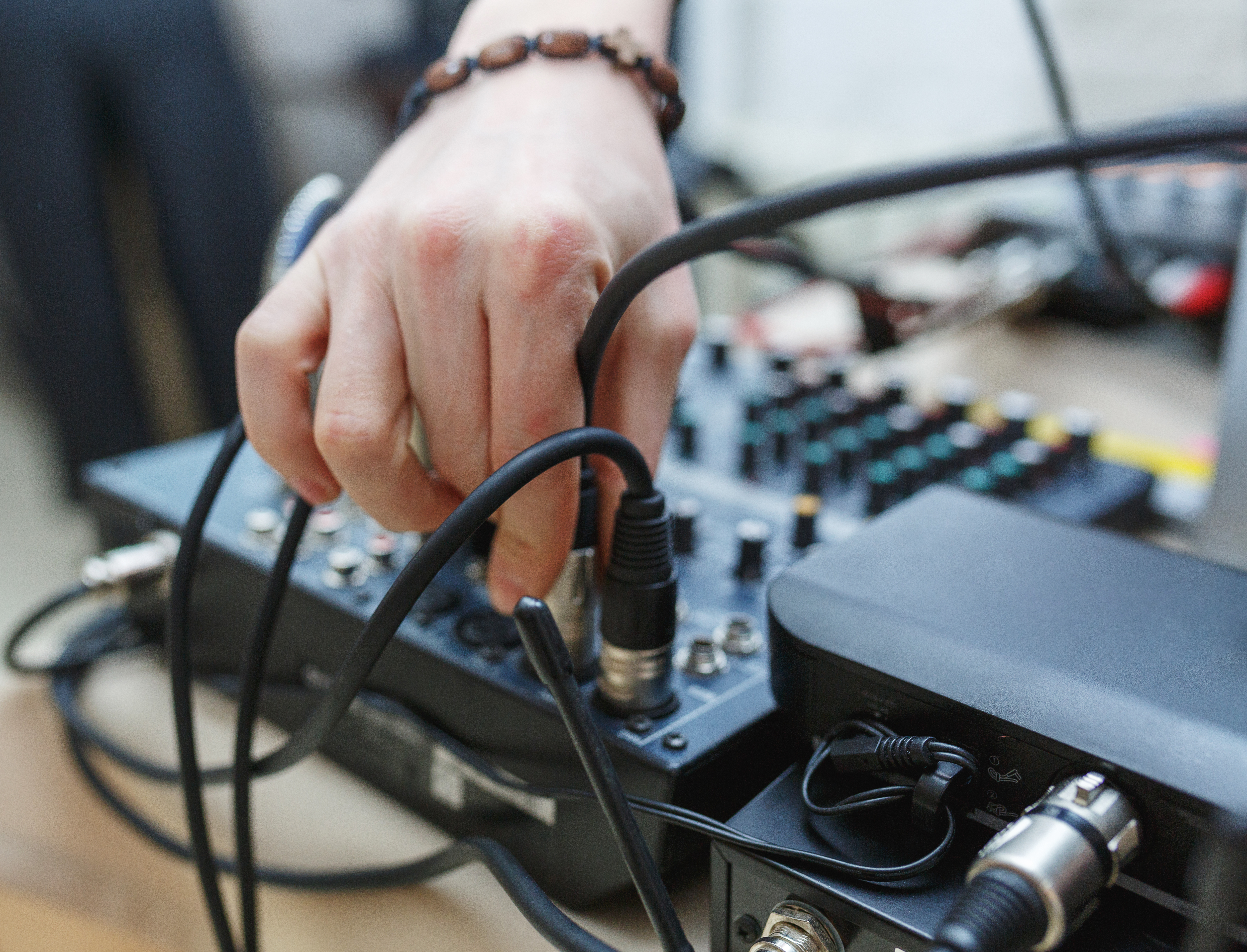DJ connects the sound equipment for the event or party. man's hand holding the audio connector on the background of the sound equipment.